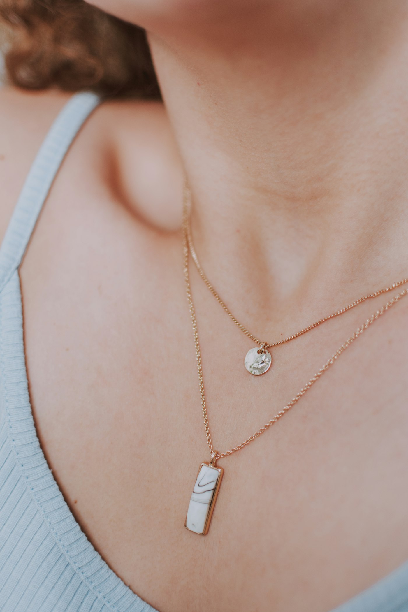 Woman wearing a gold necklace against a warm neutral background